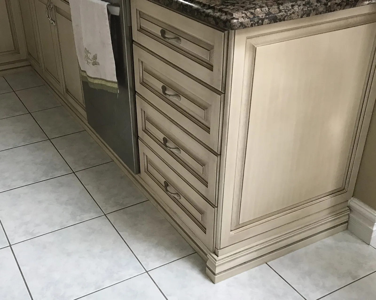 Refinished drawer fronts and door panels on a corner run, the glaze holding in the profile mouldings under dark granite