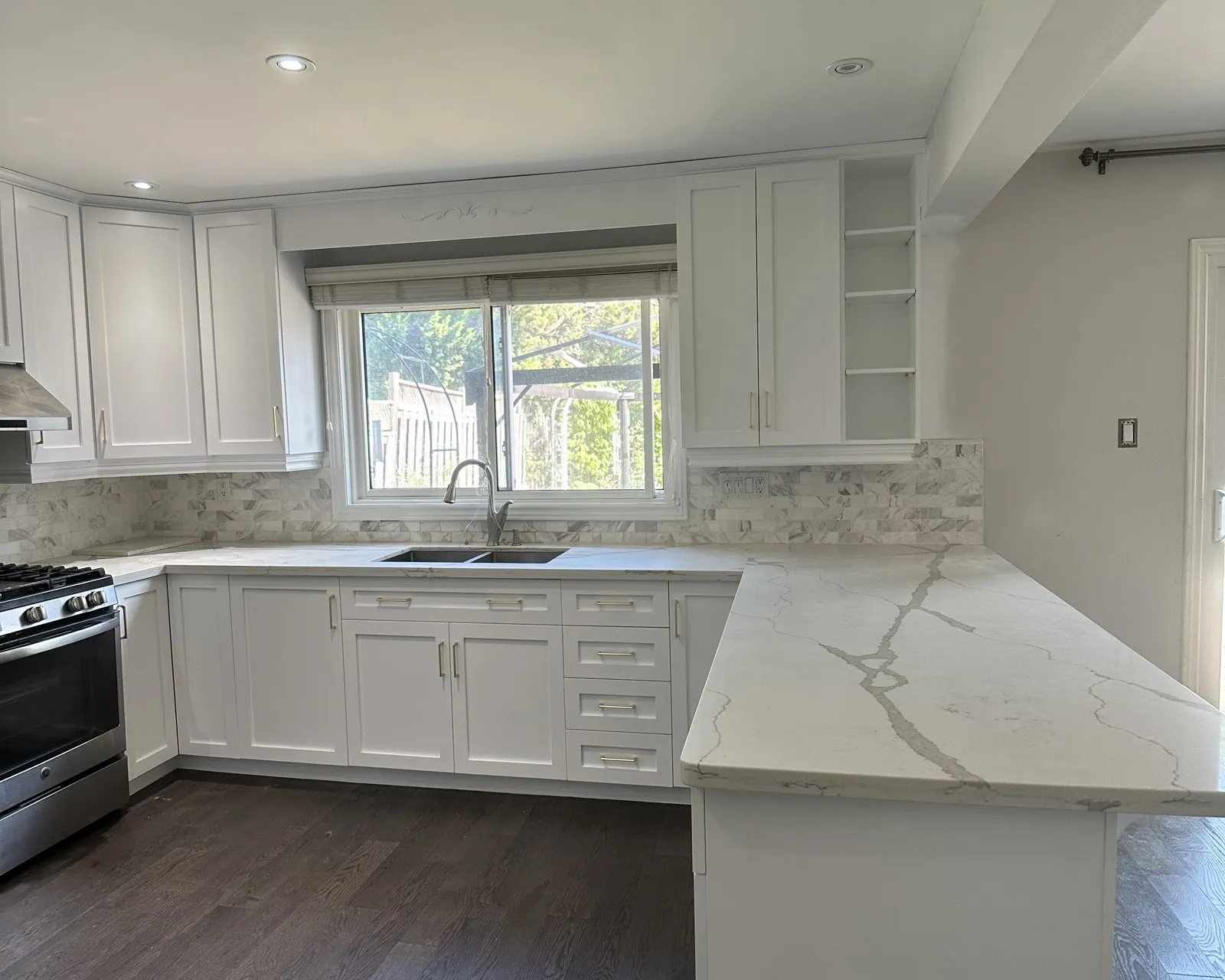 A kitchen with new white cabinet fronts and veined quartz across the counters