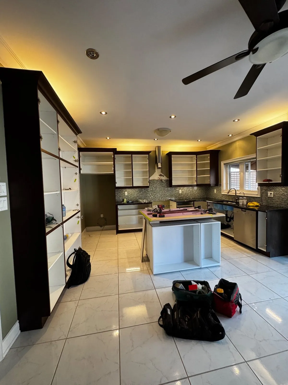 The kitchen mid-job with every door removed and two new white cabinet boxes added to the end of the island