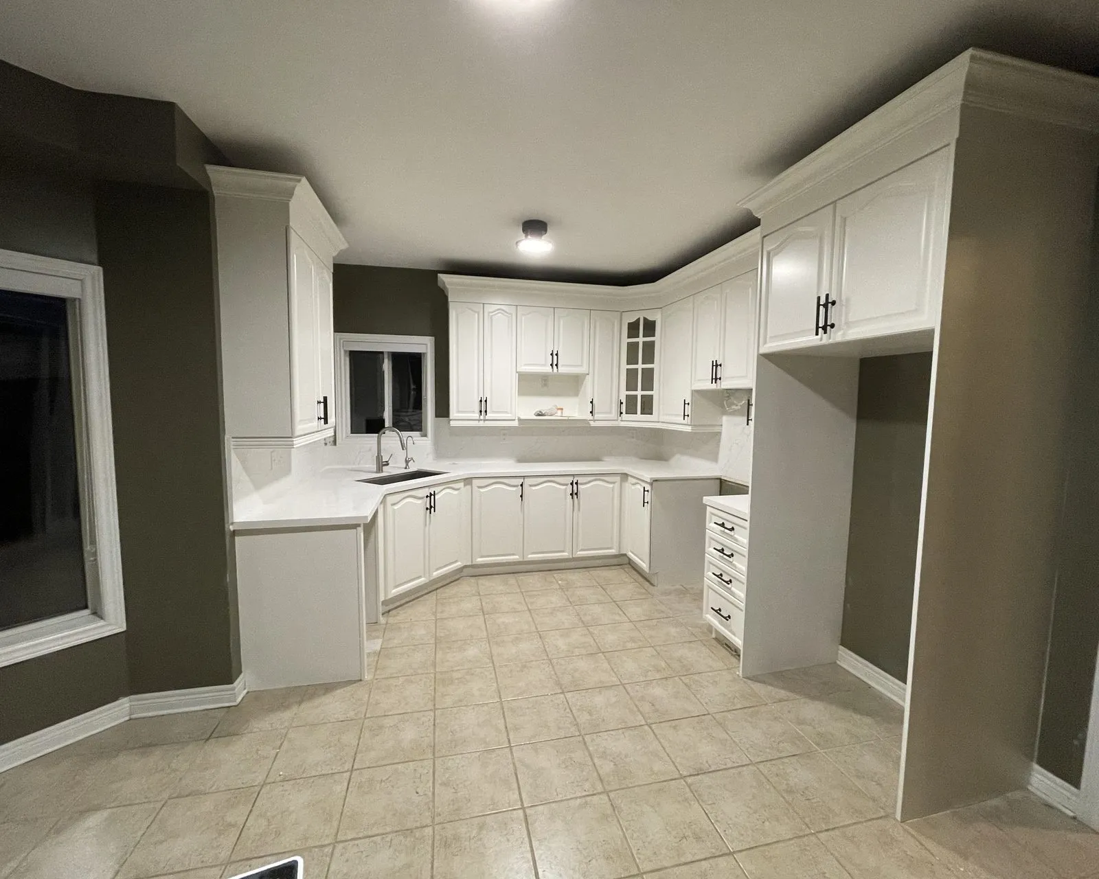 After — honey oak sprayed white, double crown and new handles, counters and backsplash by others — Wedgewood Creek, Oakville