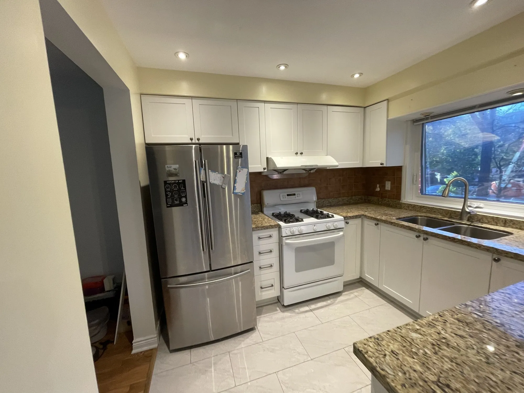 After — flat white doors refaced with MDF shaker fronts, granite and layout kept — Erindale, Mississauga