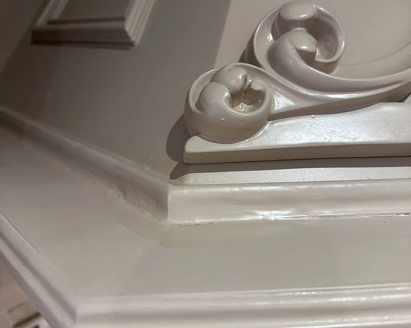 A carved scroll on a range-hood surround, finished in the same colour as the cabinetry — millwork rather than a cabinet door