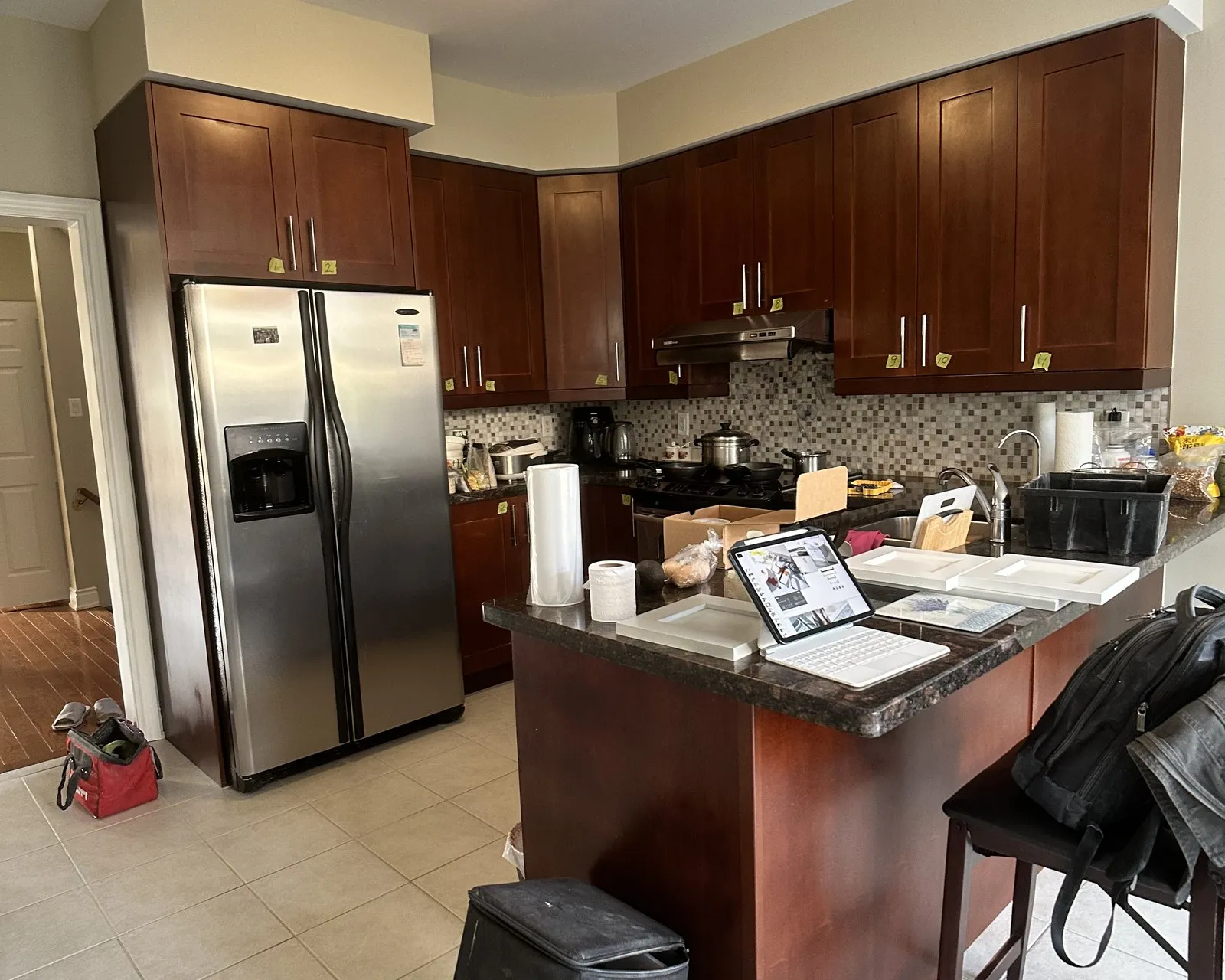 Before — A kitchen before and after. Dark cherry doors were replaced with white on the same boxes, and the granite, mosaic backsplash and tile floor all stayed