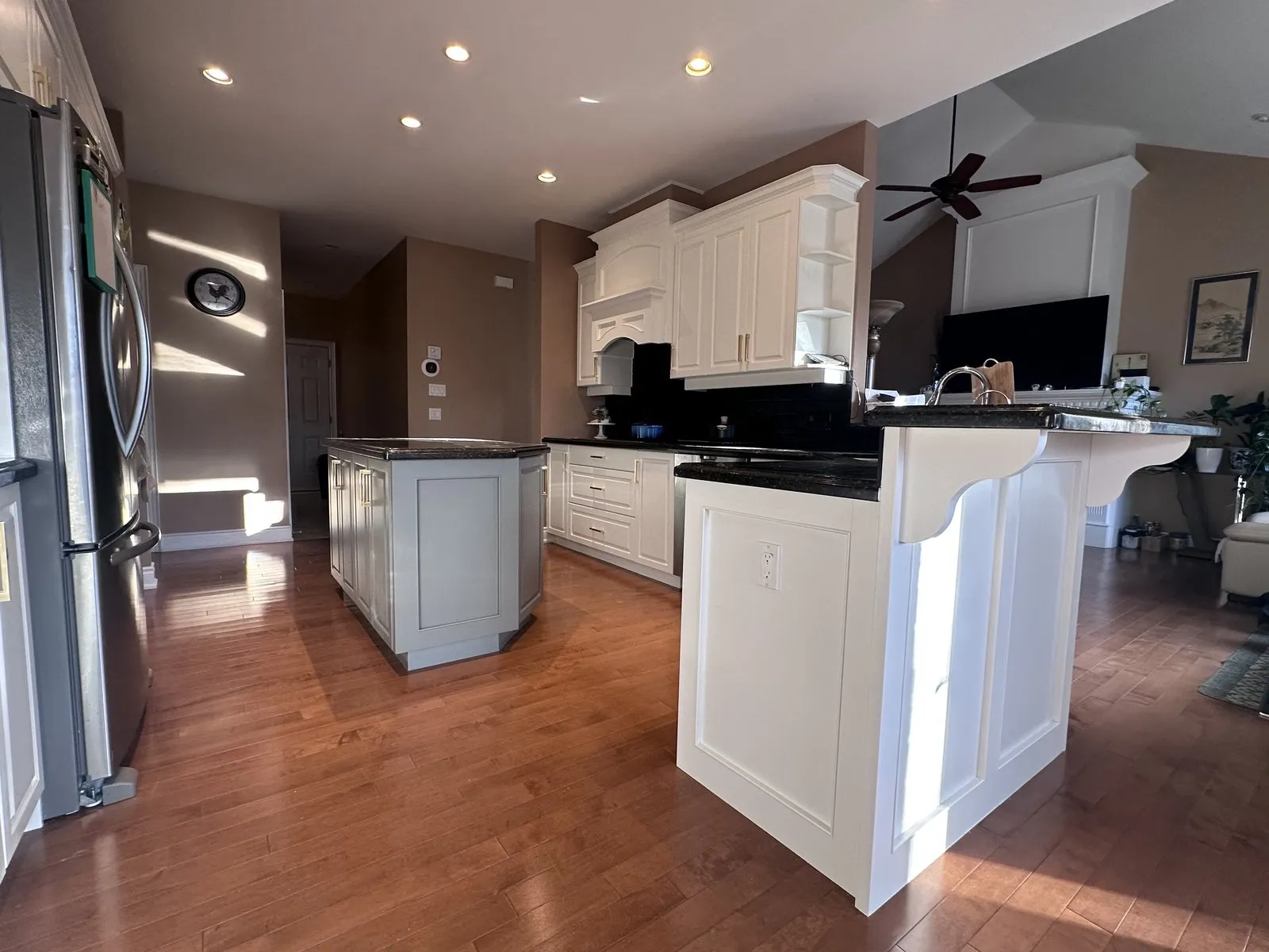 A kitchen with its original cathedral-arch doors sprayed white, keeping the black granite counters and hardwood floor