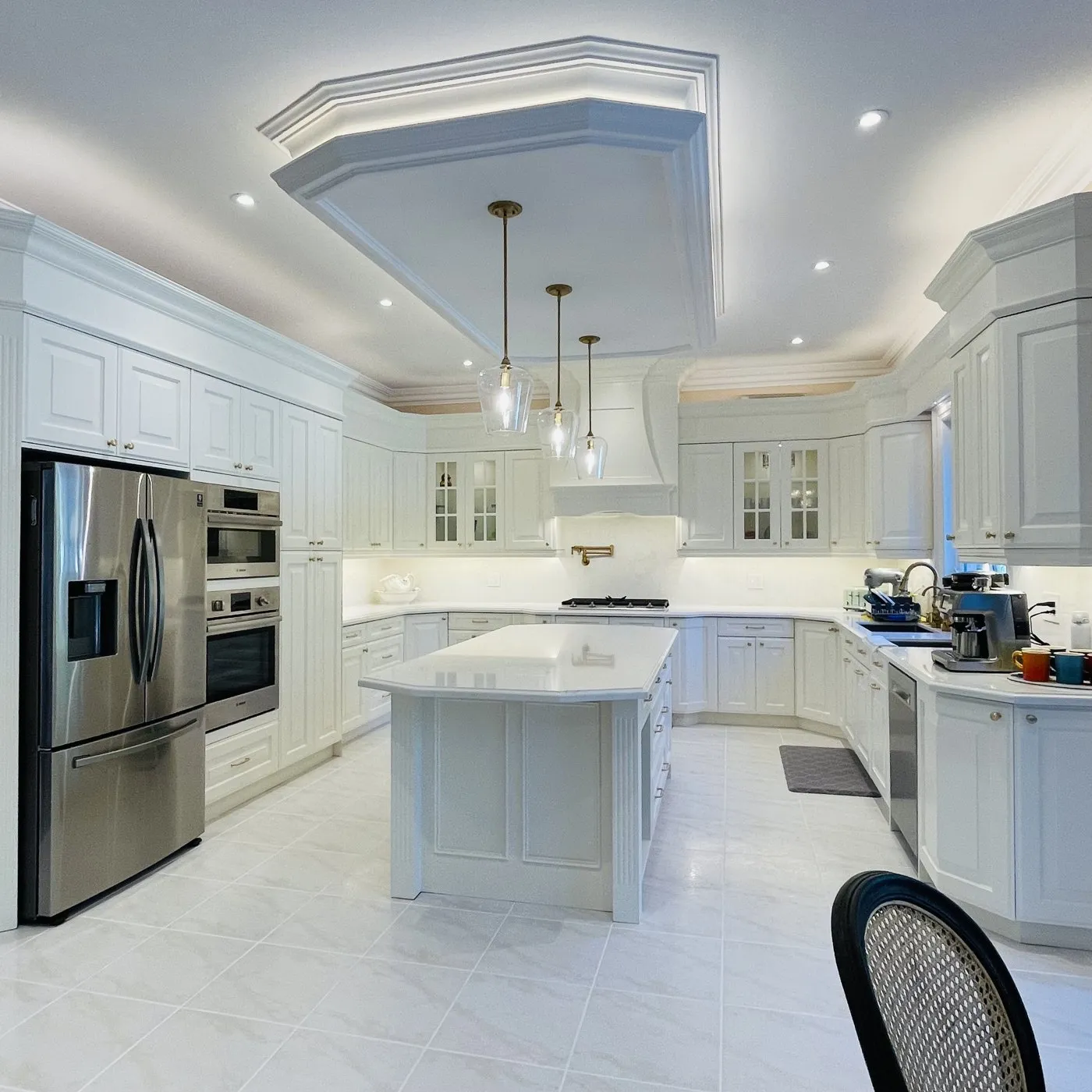 Custom cabinetry in Eastlake, Oakville — a kitchen mid-install in primed carcases, then finished in white with a fitted hood surround and coffered ceiling