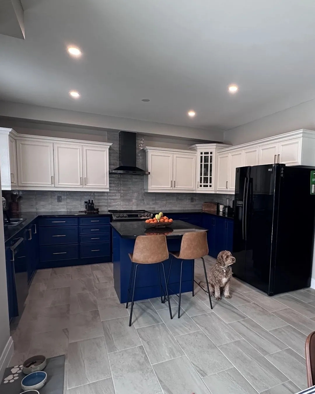 An Oakville kitchen sprayed in two colours, with cream upper cabinets, navy lower cabinets and a matching island
