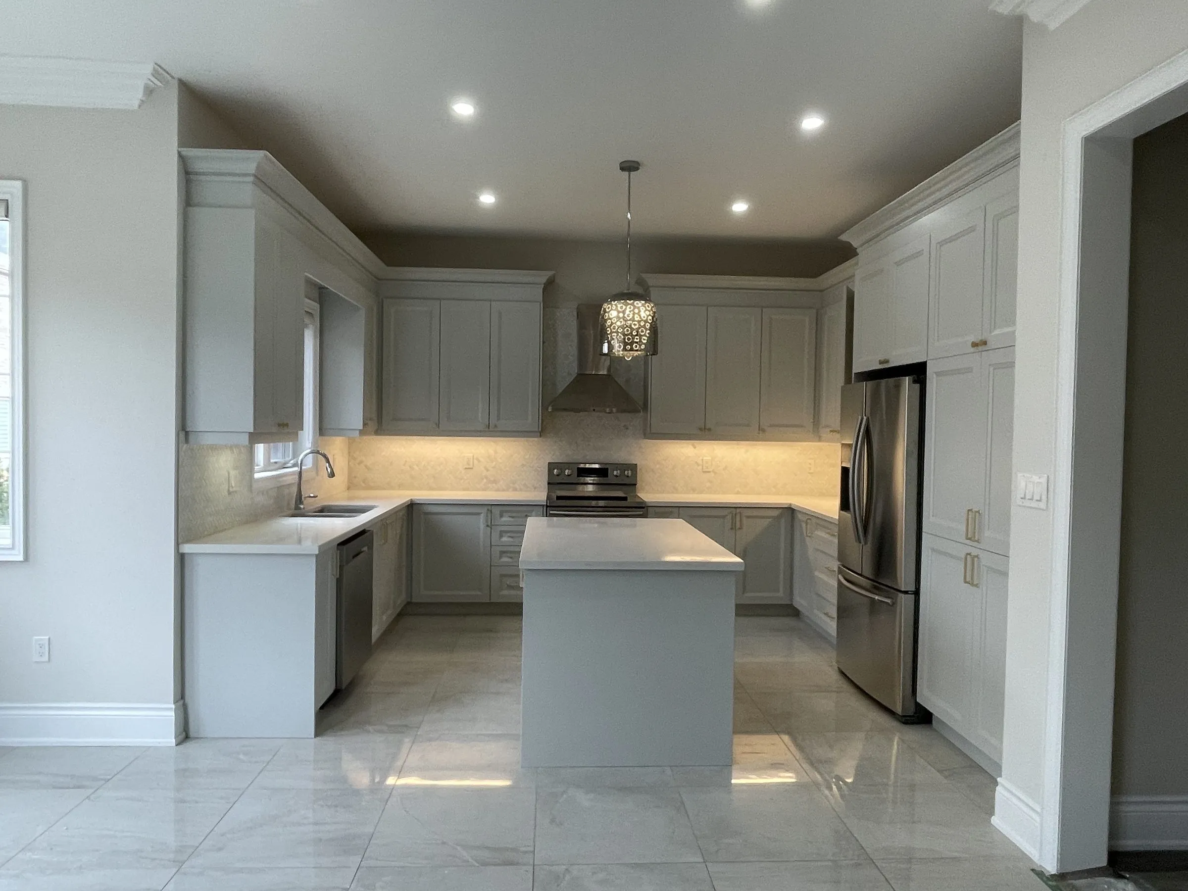 A kitchen in Glen Abbey, Oakville, refaced by Kitchen Made New, with soft grey shaker doors and crown moulding on the original frames