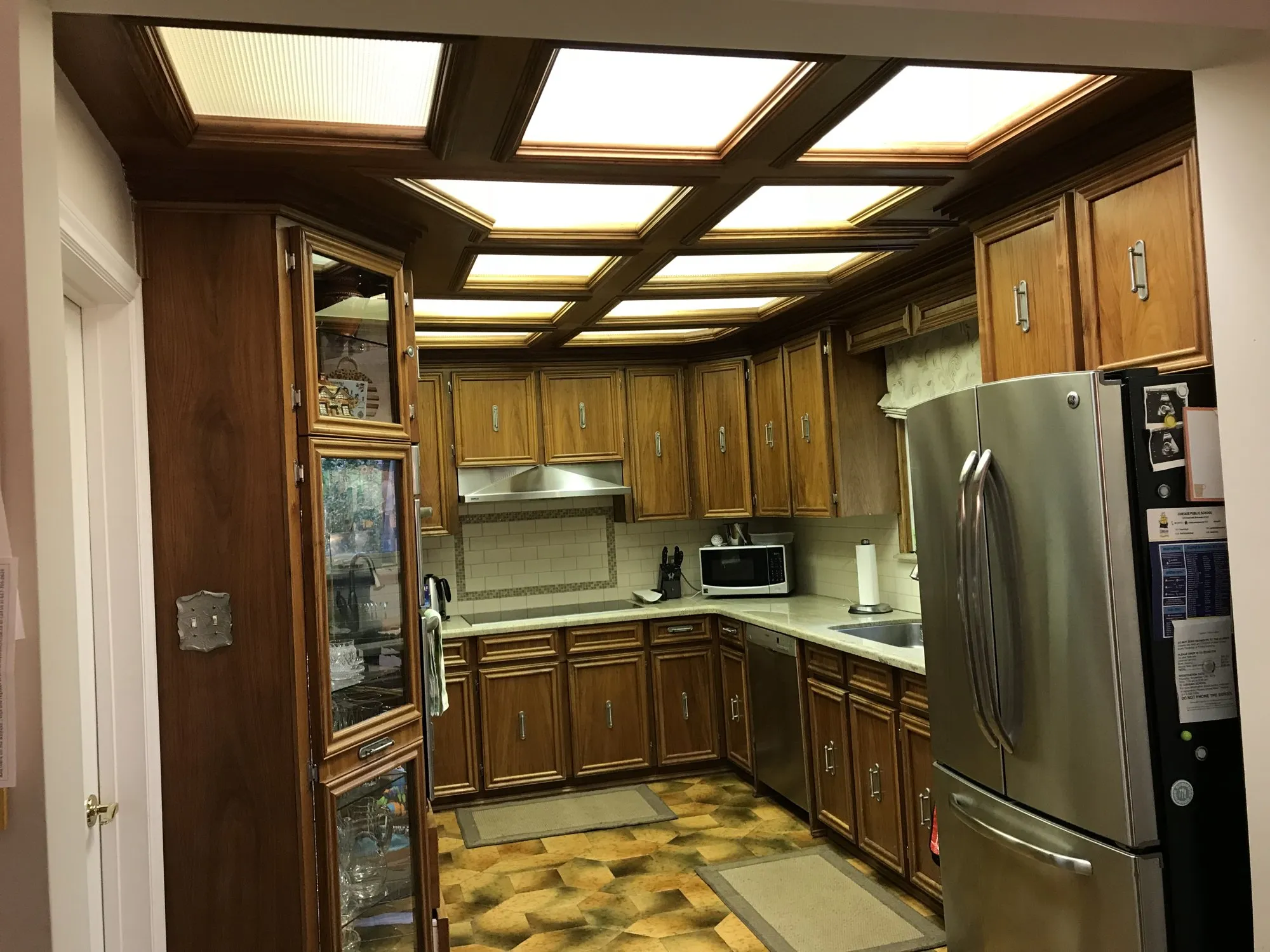Before — Kitchen cabinet refacing in Palermo, Oakville — dark oak doors and drawer fronts replaced with white raised-panel fronts on the same boxes, in the same U-shaped layout