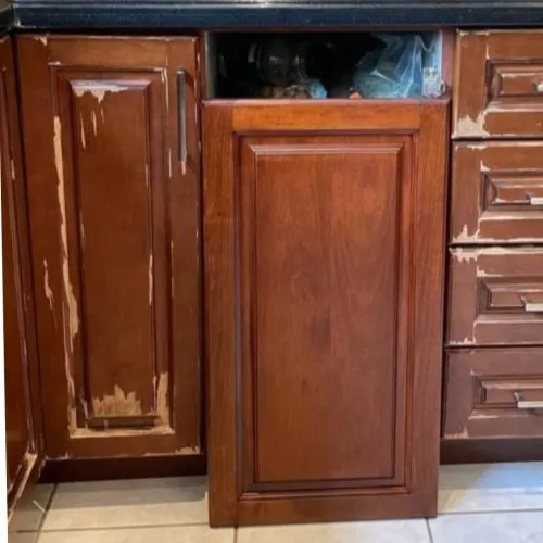 A cabinet door with the old finish worn through, next to one stripped and refinished