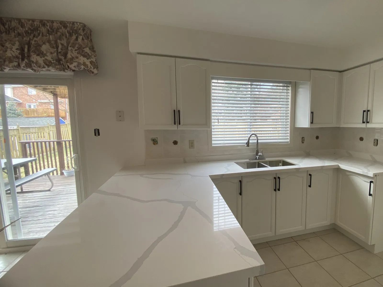 White veined quartz along a peninsula, installed next to newly sprayed white cabinets