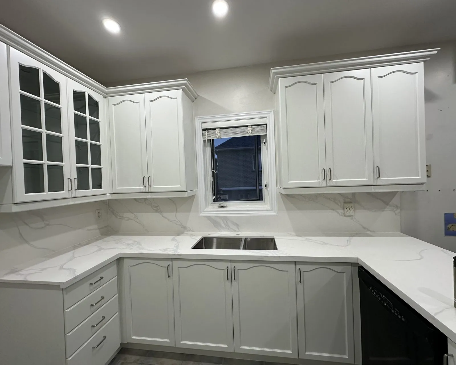 A quartz slab backsplash run full height behind the counter in an Oakville kitchen, the veining carried up the wall from the countertop